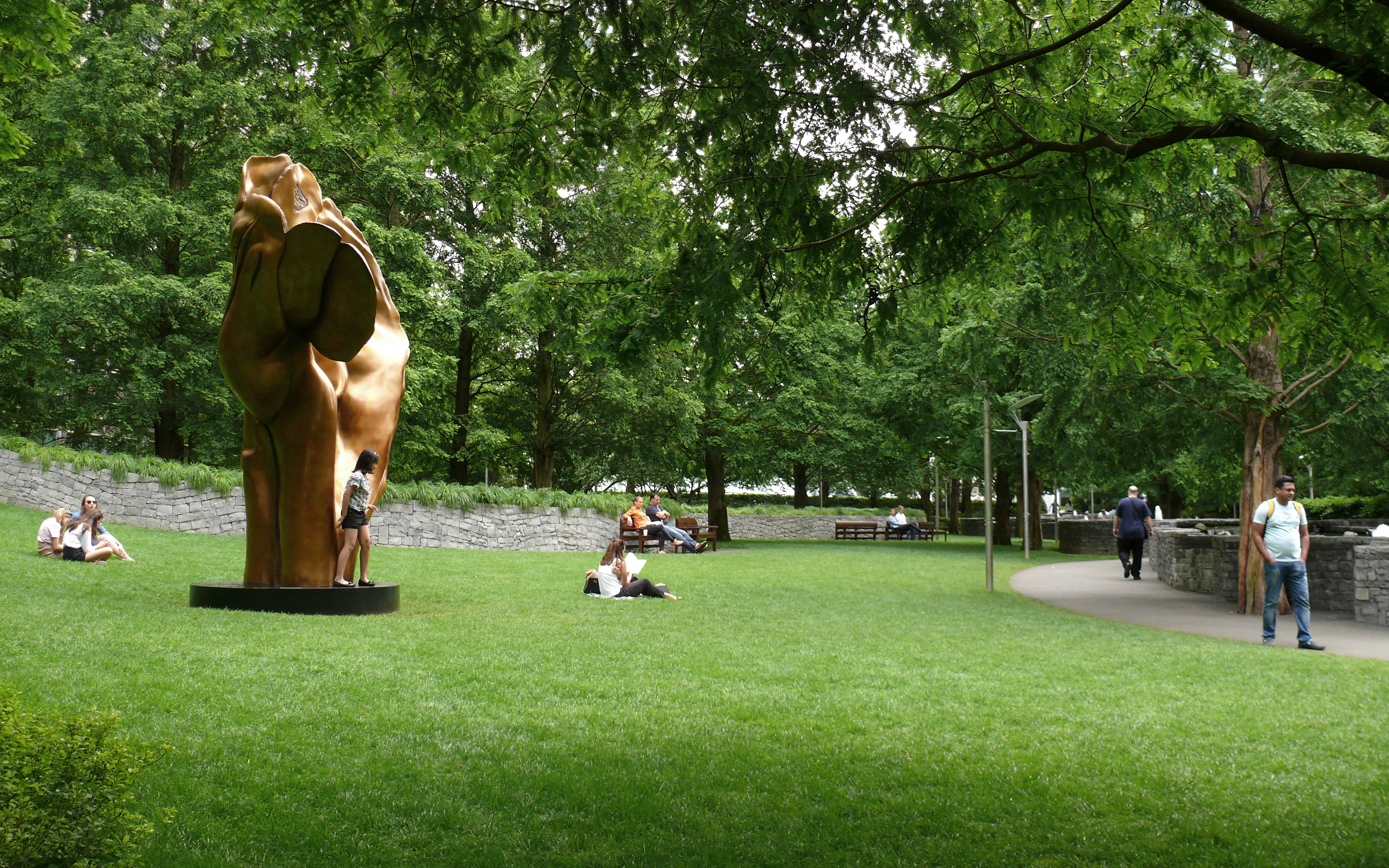 Bronze sculpture on the lawn and people relaxing in the park